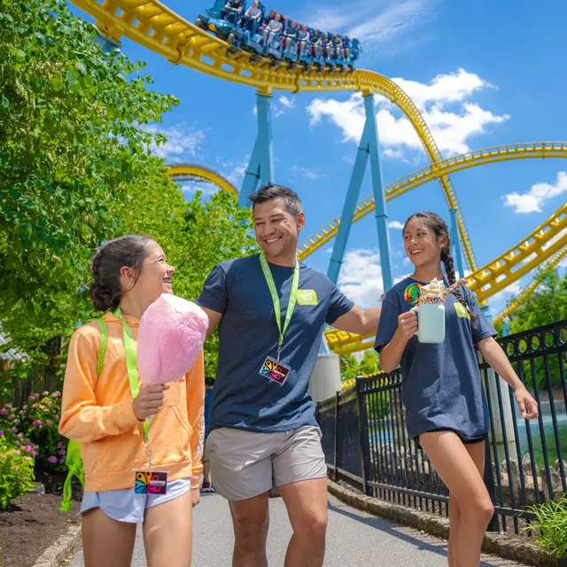 Father And Two Daughters Walking With Skyrush In Background
