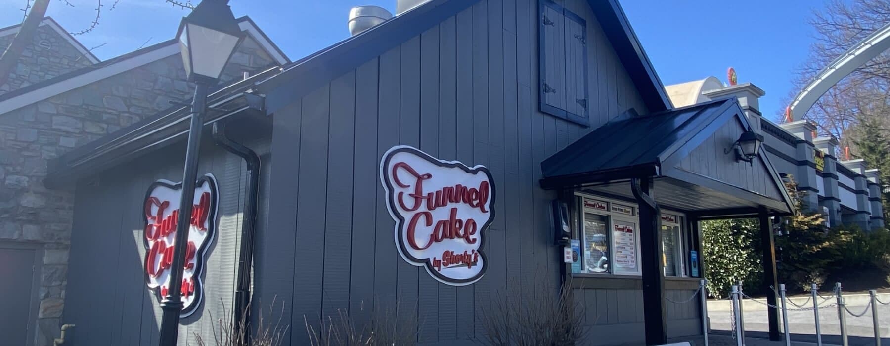 Dark grey Funnel cake building with sign and ordering window