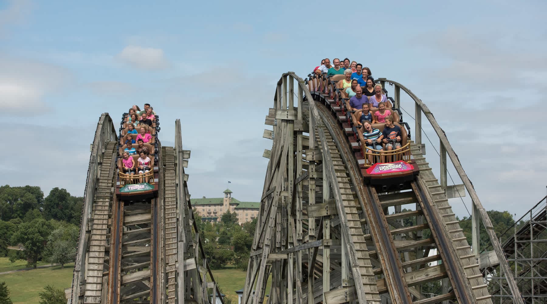 Two Lighting Racer Trains running alongside eachother full of people looking excited