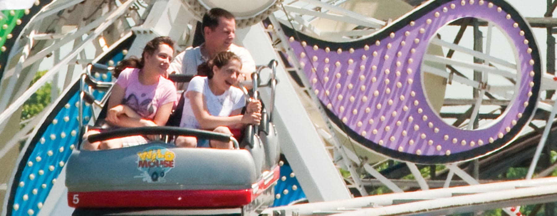 Family Riding Wild Mouse Coaster with the Ferris Wheel in background