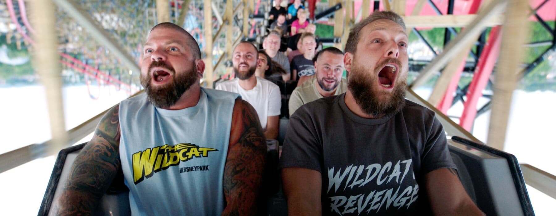 Two men wearing Wildcat Revenge shirts riding Wildcat's Revenge front row together