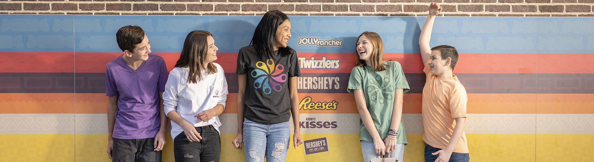 Teens jumping in front of pinwheel logo at Hersheypark