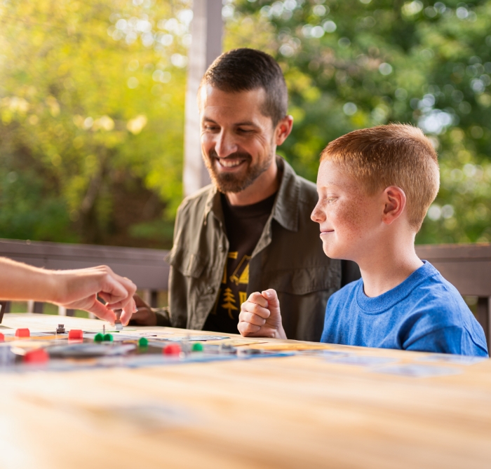 Dad and son playing boardgame in campground.