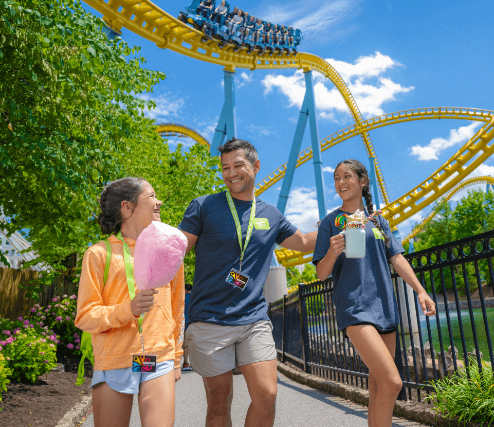 Family walking through Hersheypark with a rollercoaster overhead